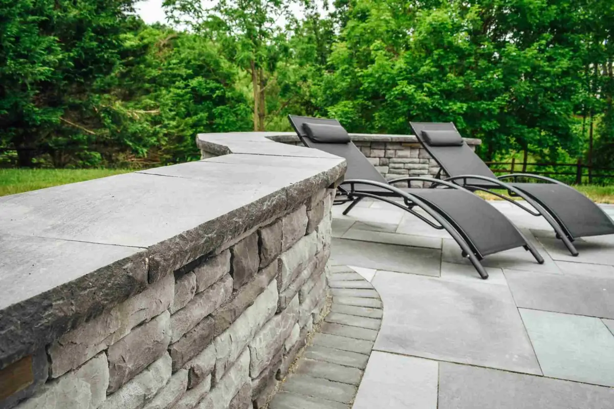 Stone wall patio with lounge chairs
